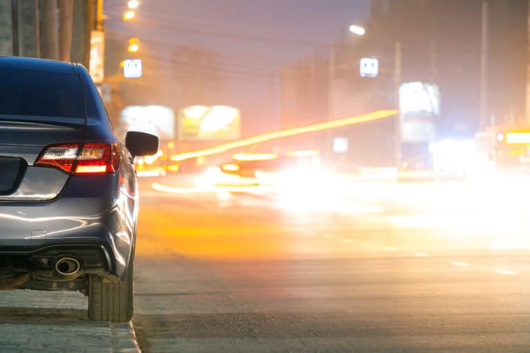Close up of parked car on roadside at night with blurred view of