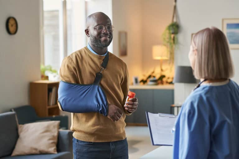 Smiling Black Man with Broken Arm Talking to Nurse