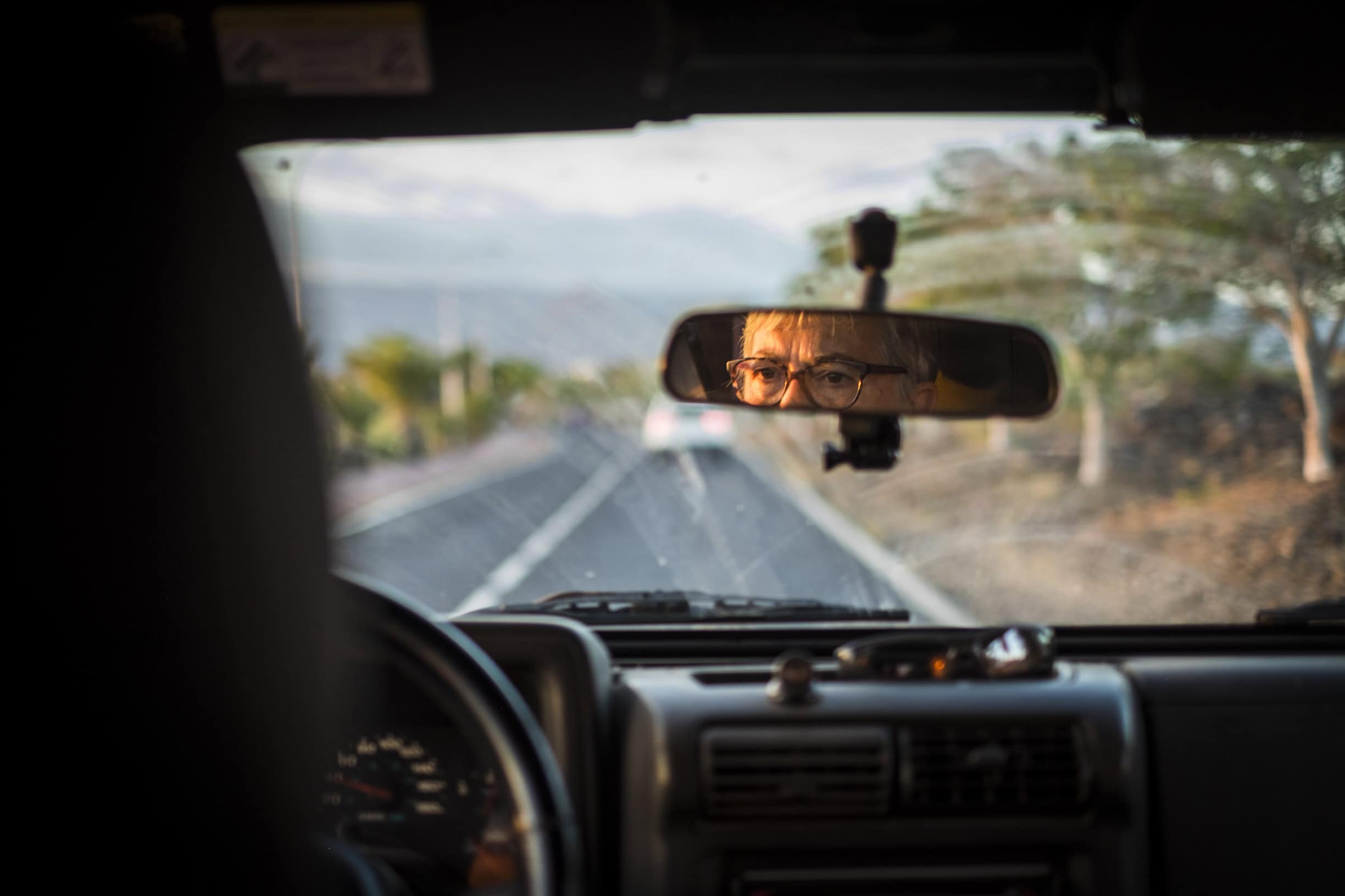adult senior woman drive the car. inside point of view with focus on the mirror to see her concentrated face and expression while driving with care. transport and life concept