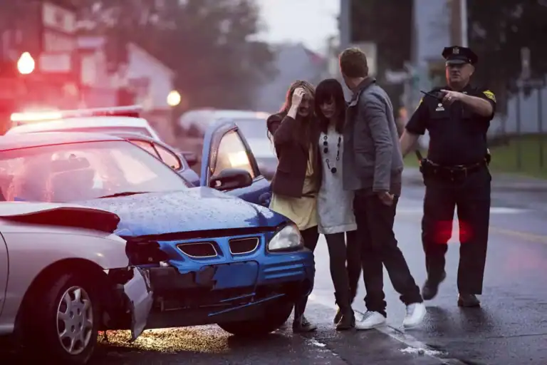 Police officer speaking with a driver beside two cars after a crash