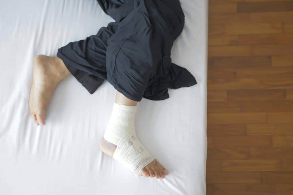 Injured man with bandaged foot lying on bed
