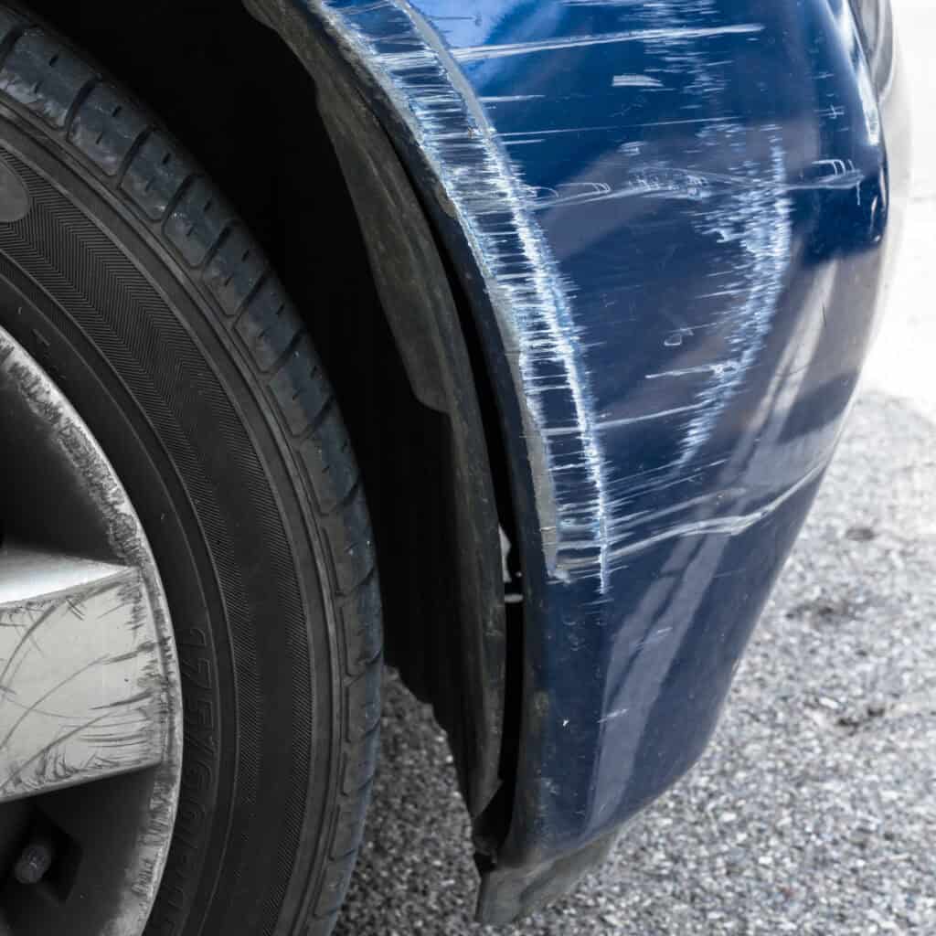 Accident damage to the front side of a blue car.