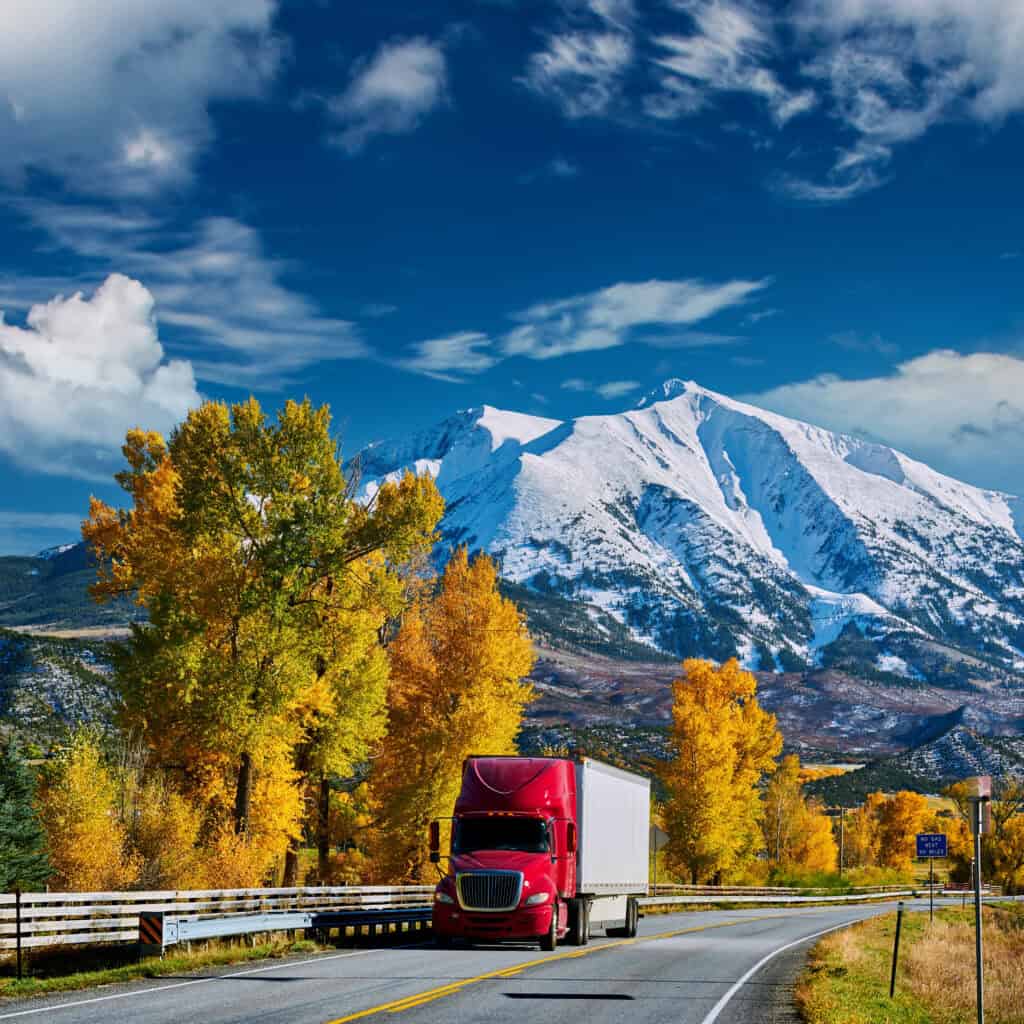 Red truck on highway in Colorado at autumn, USA. Mount Sopris landscape.